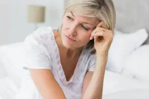 27115743 - closeup of a tensed mature woman sitting in bed at home